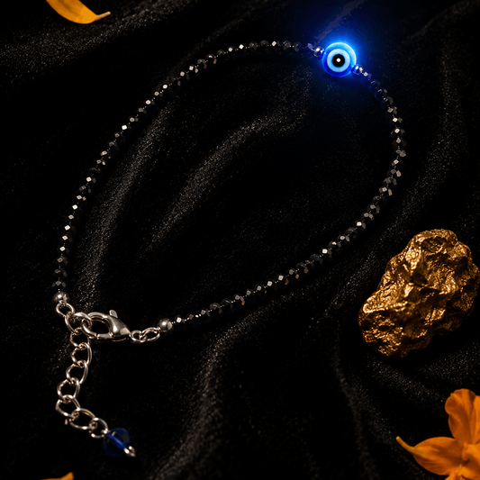 Bracelet with glowing blue stone on a dark background with gold leaf