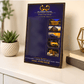A custom framed metal affirmation board with a dark navy blue background and gold trim, styled on a white tabletop next to a small potted succulent and books.