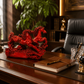 Red horse sculpture on a wooden desk with a notebook and pen, in an office setting.