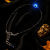 Bracelet with glowing blue stone on a dark background with gold leaf