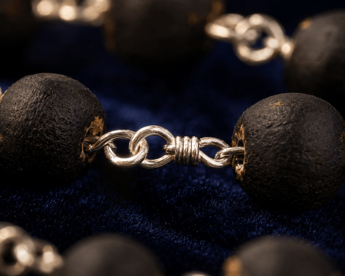 Close-up of a silver chain with black beads on a dark background