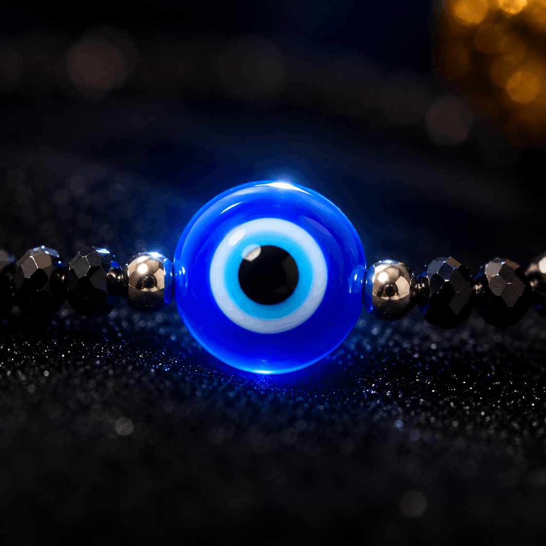 Blue evil eye bead on a black beaded bracelet with a blurred background