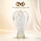 A clear glass angel figurine standing on a pedestal, centered against a soft warm beige background with draped fabric. Above the figurine, the text 'MILLIONAIRE'S MIND HUB' and the tagline 'Think Rich & Become Rich' appear with a gold infinity symbol logo.