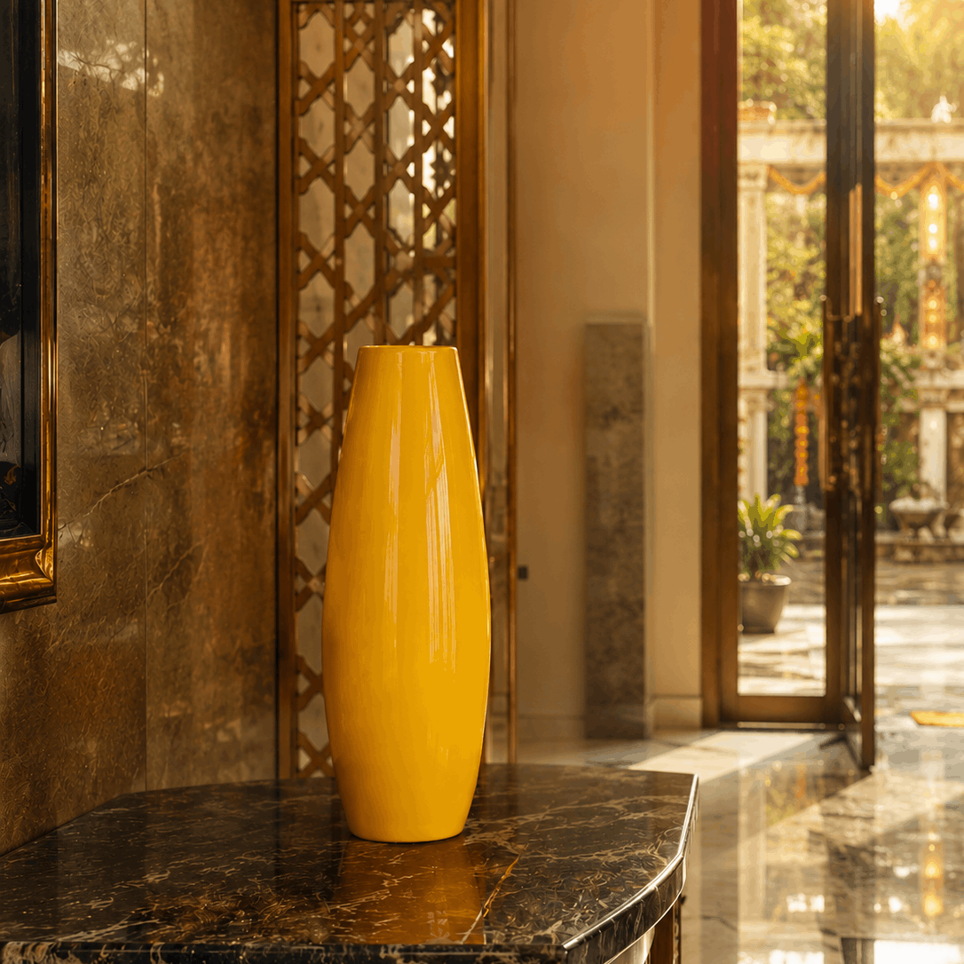 Yellow vase on a marble surface with a decorative wall and open door in the background