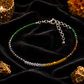 Multicolored beaded bracelet on a dark fabric background with gold rocks and a candle.