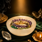 Colorful beaded bracelets in a white dish with incense and candles on a dark background