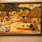 Framed artwork depicting a village scene on a wall above a wooden console table.