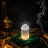 Selenite crystal on a green cushion with coins and a candle in a mystical setting