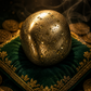 Gold rock on a green cushion with coins around, dark background
