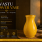 Yellow vase on a wooden surface with Vastu information text on a dark background