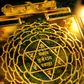 Decorative item with gold and green design, featuring sacred symbols and text.