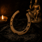 Rusty horseshoe with a candle and statue in the background