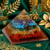 Pyramid-shaped crystal orgone with colorful layers on a green fabric background